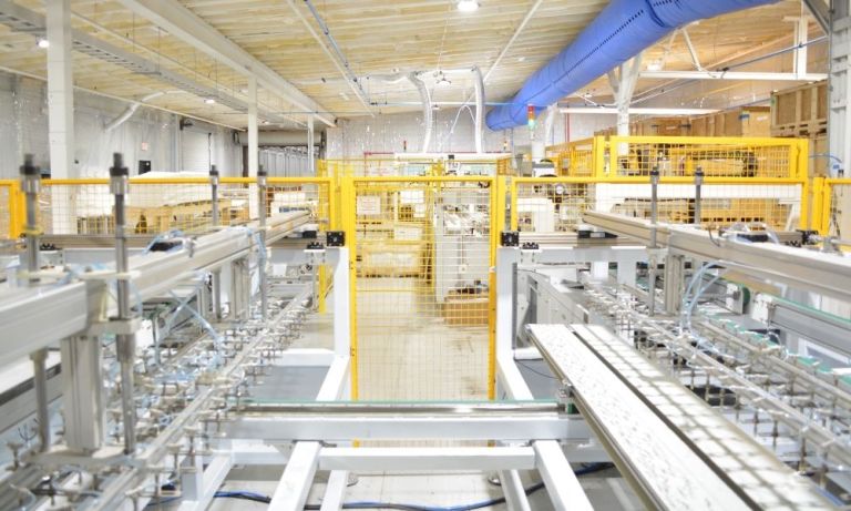 High-angle view down an automated assembly line with yellow safety guards.