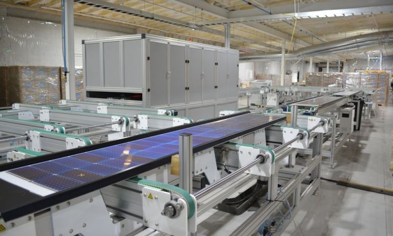 Solar panel sections moving down a motorized belt conveyor.